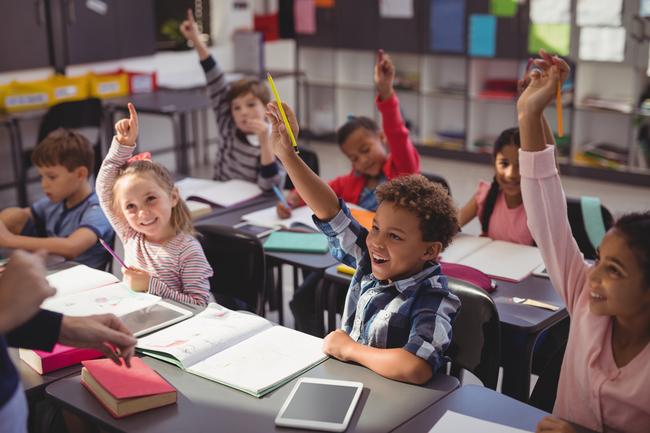 Youth in classroom raising hands