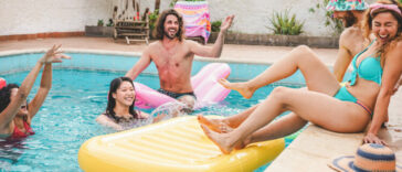 Young people hanging out by a pool with a big yellow float.