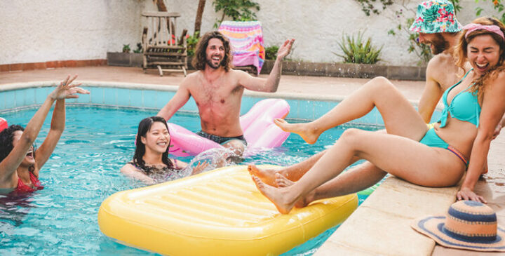 Young people hanging out by a pool with a big yellow float.