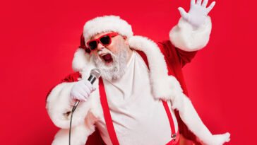 Photo of Santa Claus singing 9 classic Christmas songs on a mic.