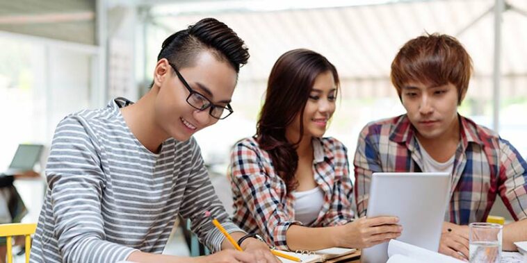 A young woman and two young men studying together.