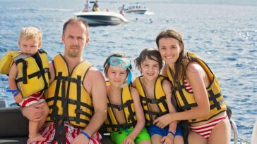 On a boat, a family smiles while wearing life jackets