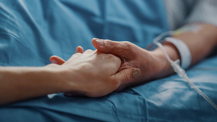 a person holding hands with someone in a hospital bed