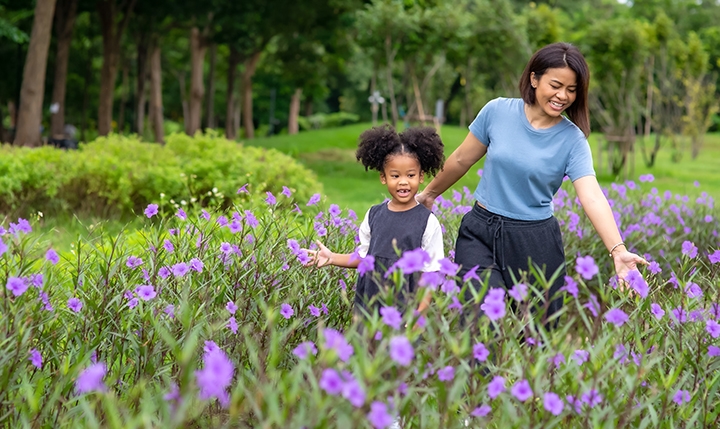 Happy family mother with little daughter holding hands and walking together in the garden Smiling mom with cute child girl enjoy and having fun outdoors celebrating mother's dsy in Central Florida