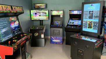 Photo of multiple game machines inlcuding Mortal Kombat, Golden Tee and Arcade Legends inside a man cave.