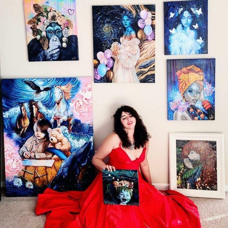 female artist sitting on the floor, surrounded by her paintings