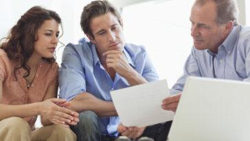 Couple going over paperwork with financial advisor to achieve financial success.