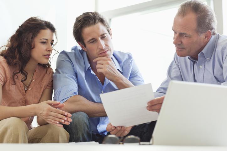 Couple going over paperwork with financial advisor to achieve financial success.