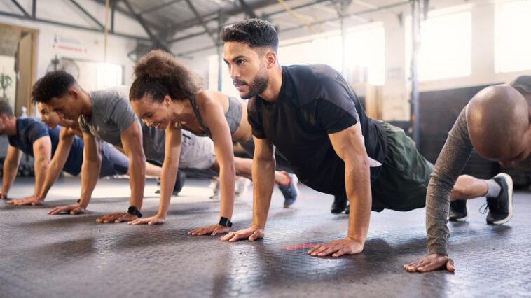 Fitness, gym with men and women doing plank, strong and exercise for muscle, cardio and endurance in workout class. Health, wellness and diversity, body training and healthy active challenge.