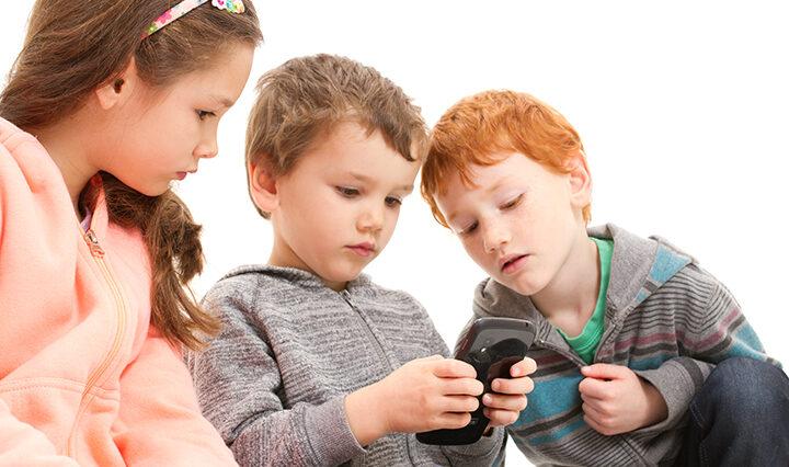 Kids playing games on mobile phone. Learn how social media can impact their mental health.