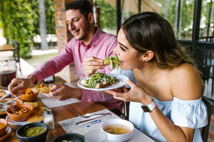 young latin woman eating mexican tacos on a restaurant terrace, new eateries in Orlando.