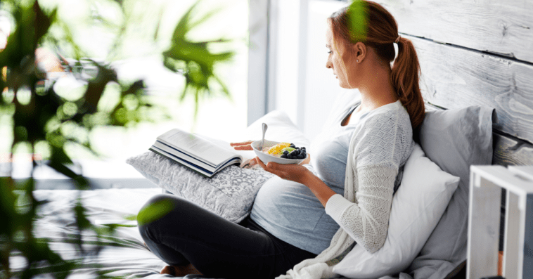 Young pregnant woman practicing yoga at home