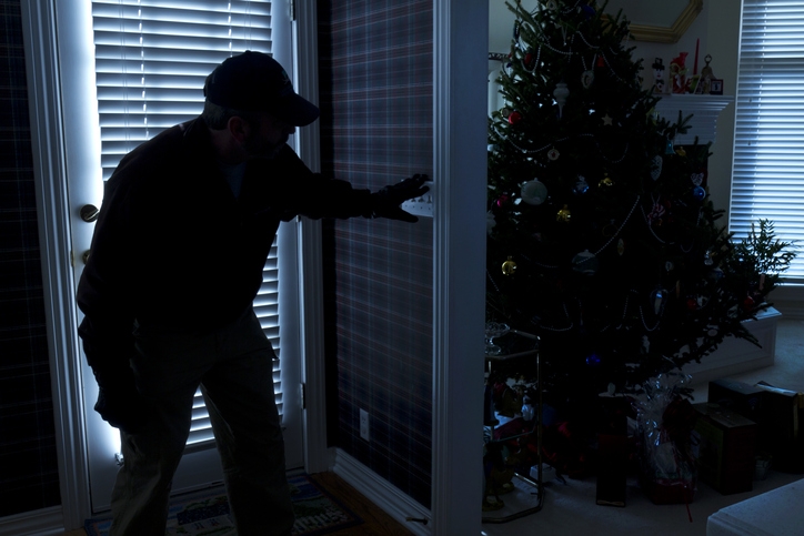 This photo illustrates a burglary or thief breaking into a home at night through a back door during the Christmas Holiday Season.