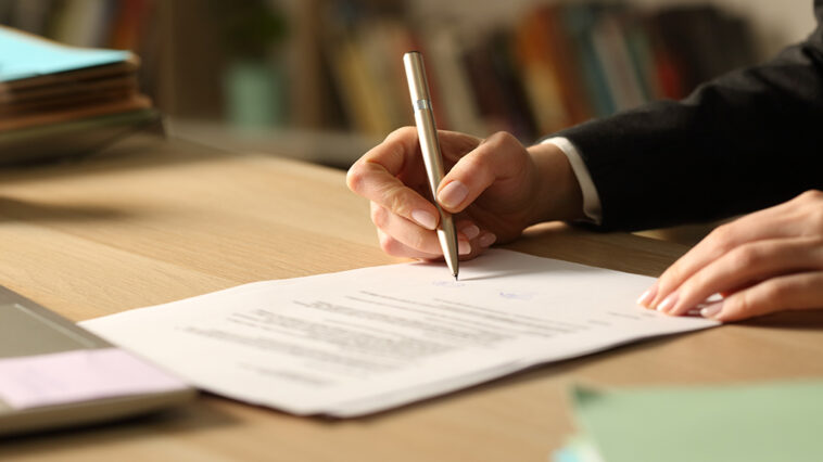 close up of person signing papers